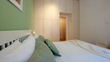 Ein Schlafzimmer mit einem Bett, Kissen, einer Nachttischlampe und einem Kleiderschrank.