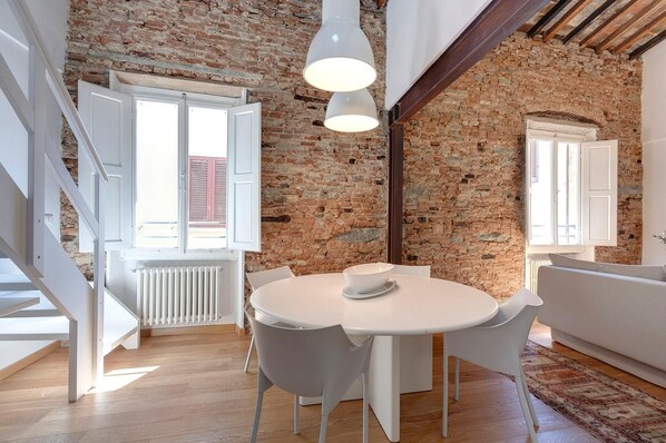 A dining area with a round table, white chairs, and pendant lights. - View of the Duomo • In the Heart of Florence (FIRENZE)