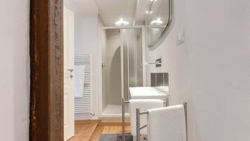 Une salle de bain moderne avec une douche à parois de verre, un lavabo blanc et un porte-serviettes.