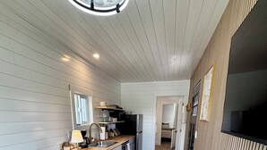 Een knus woongedeelte met een kitchenette, een bank en een houten vloer.