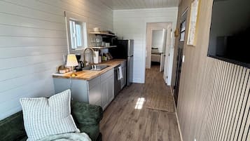 A compact living space with a kitchenette, a sofa, and a wooden floor.