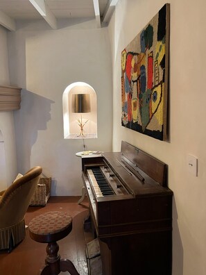 A piano in a room with a patterned rug, a lamp, and a chair. - House with a large yard, perfect for a family vacation. (La Roche-sur-le-Buis)