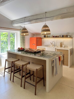 A modern kitchen with a central island, bar stools, a hanging light fixture, and a vintage orange refrigerator. - House with a large yard, perfect for a family vacation. (La Roche-sur-le-Buis)