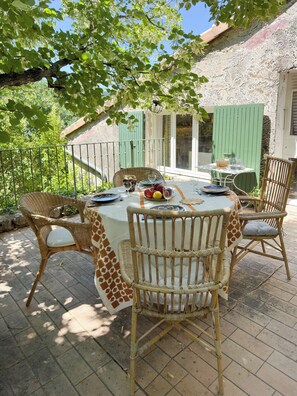 An outdoor dining area with wicker chairs and a table set for two, surrounded by greenery and a stone wall. - House with a large yard, perfect for a family vacation. (La Roche-sur-le-Buis)