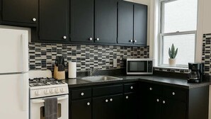 Una cocina moderna con armarios negros, un refrigerador blanco, una estufa, un microondas y un fregadero.