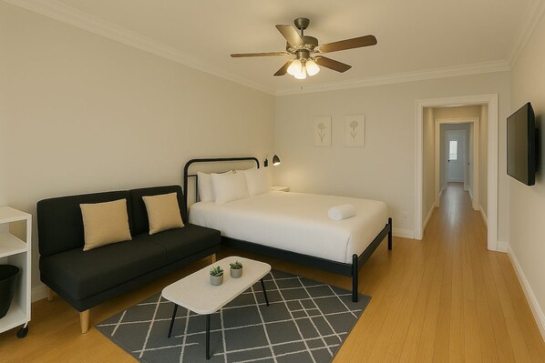 A bedroom with a bed, a nightstand, a desk, a chair, a ceiling fan, and a TV.