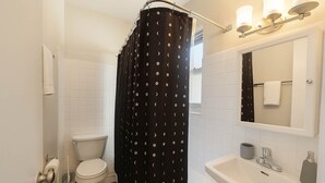 Een badkamer met toilet, wastafel en douchegordijn.