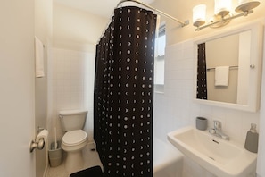 Ett badrum med toalett, handfat och duschdraperi.