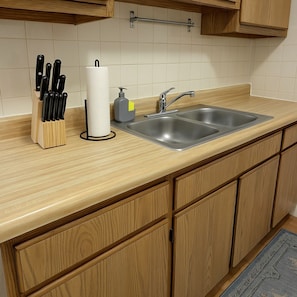 Una cucina con un piano di lavoro in legno, un lavello e un portacoltelli.