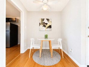 A dining area with a round table, two chairs, a ceiling fan, and a kitchen in the background. - Bright & Cozy Chicago 1BR | Near Dining & Transit (Chicago)