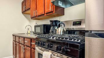 A kitchen with wooden cabinets, a stainless steel stove, a microwave, and a refrigerator.