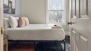 A bedroom with a bed, a window, and a door. - Chic, Quiet 1BR Near Dining Options– Perfect for 2 (Chicago)