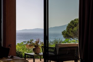 Una habitación con vistas al mar y a las montañas, una mesa con un florero y una silla.