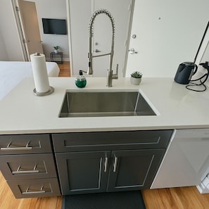 A modern bathroom with a sink, a toilet, a mirror, and a shower area. - Modern Studio on Broadway (Chicago)
