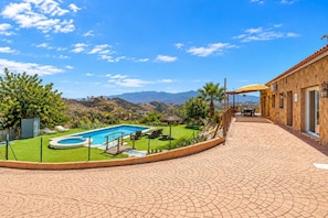 A pool area with a clear view of mountains, a fenced lawn, and a building with a tiled patio. - Villa Los Castros | Authentic Andalusian Villa in Bédar (Bédar)
