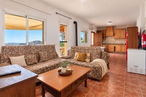 A living room with patterned sofas, a wooden coffee table, and a view of the outdoors. - Villa Los Castros | Authentic Andalusian Villa in Bédar (Bédar)