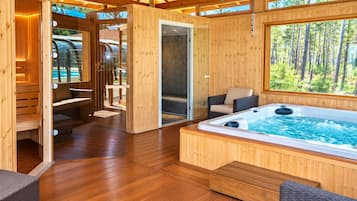 Une cabane en bois dotée d’un bain à remous, d’un espace salon et offrant une vue sur la forêt.