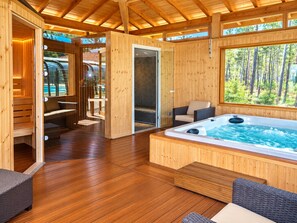 A wooden cabin with a hot tub, seating area, and a view of the forest. - Villa for 6 people at Domaine des Grands Lacs – Pools & Lake (Parentis-en-Born)