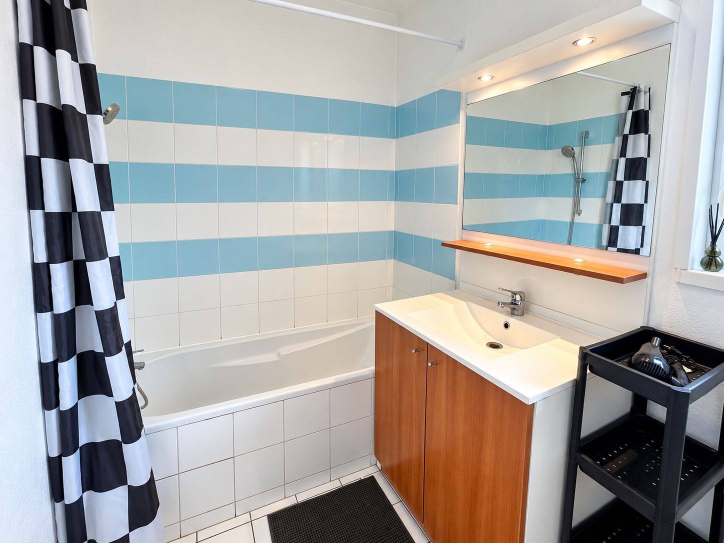 A bathroom with a bathtub, a sink, a mirror, and a shower curtain.