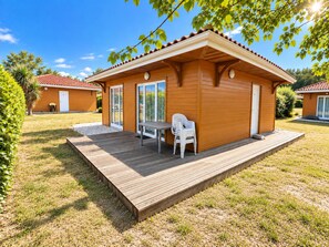 Una cabana de fusta amb terrassa i taula amb cadires.
