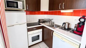 A compact kitchen with a microwave, toaster, kettle, and coffee maker.