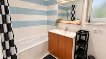 A bathroom with a bathtub, a sink, a mirror, and a shower area.