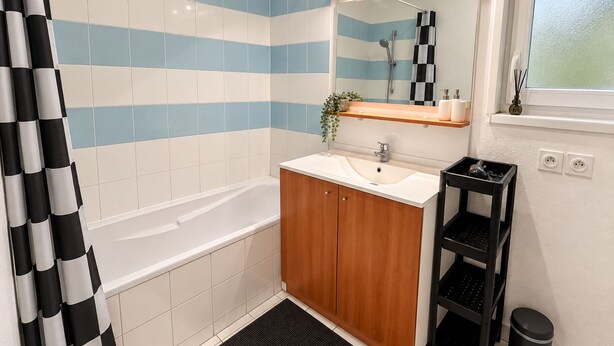 Ein Badezimmer mit Badewanne, Waschbecken, Spiegel und Duschbereich.