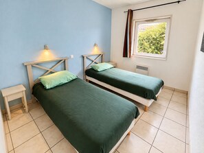 Una habitación con dos camas individuales, una ventana con vistas a zonas verdes y un radiador.