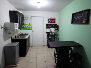 A compact kitchen with a microwave, stove, and a small dining area with a table and chairs.
