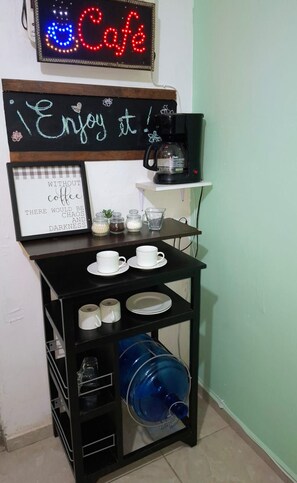 A cafe setup with a coffee machine, cups, and a chalkboard sign.