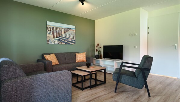 A living room with a sofa, a coffee table, a TV, and a chair.