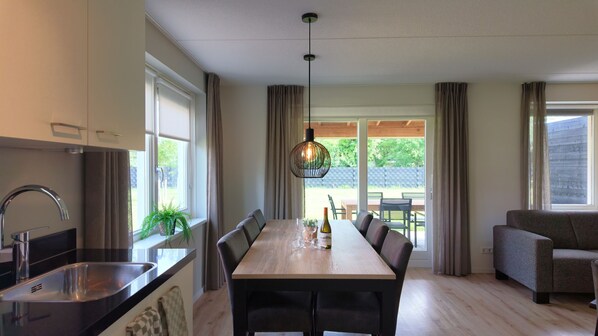 A modern kitchen with a built-in sink, a dining area with a wooden table, and a seating arrangement.