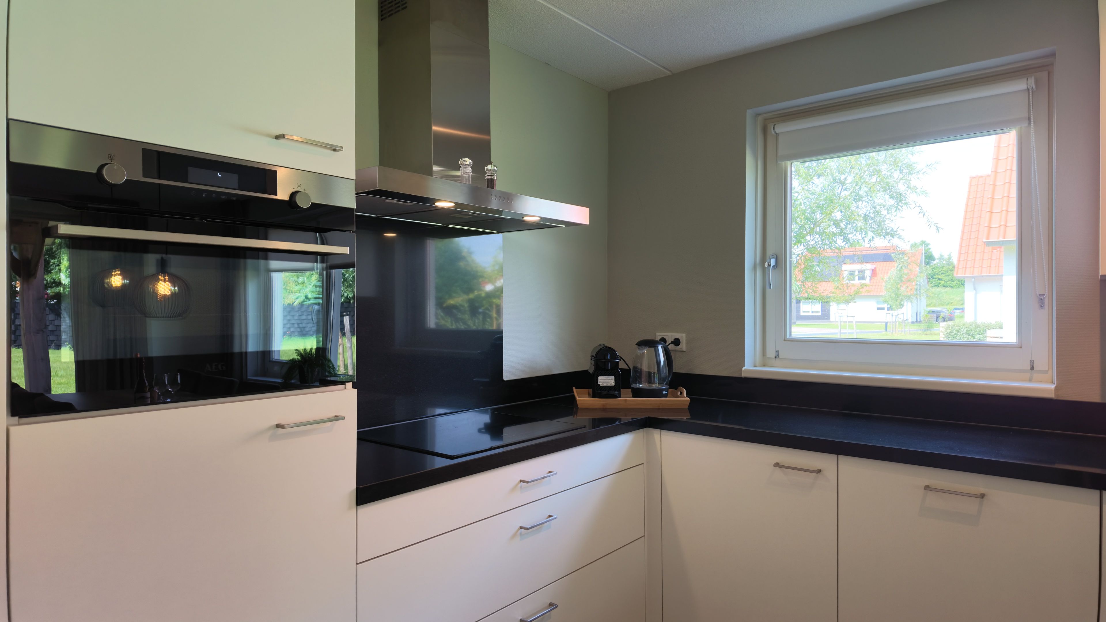 Una cucina moderna con forno a incasso, una finestra vista esterna e una macchina da caffè sul bancone.