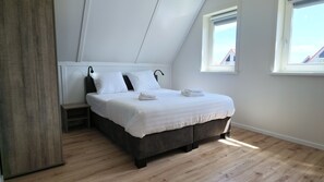 A bedroom with a bed, bedside tables, and a window.