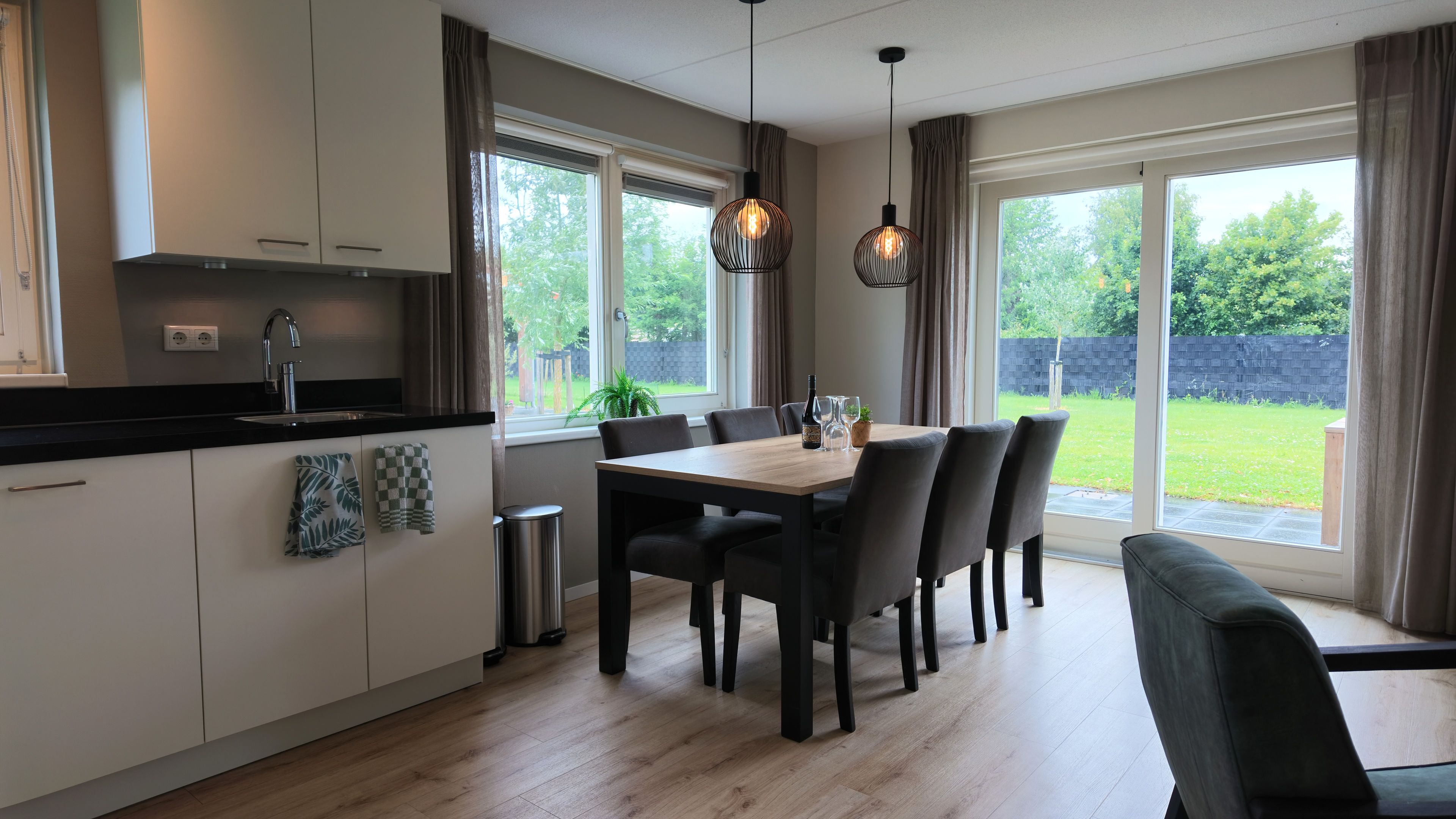 Une cuisine moderne avec un coin repas, de grandes fenêtres et une vue sur l’extérieur.