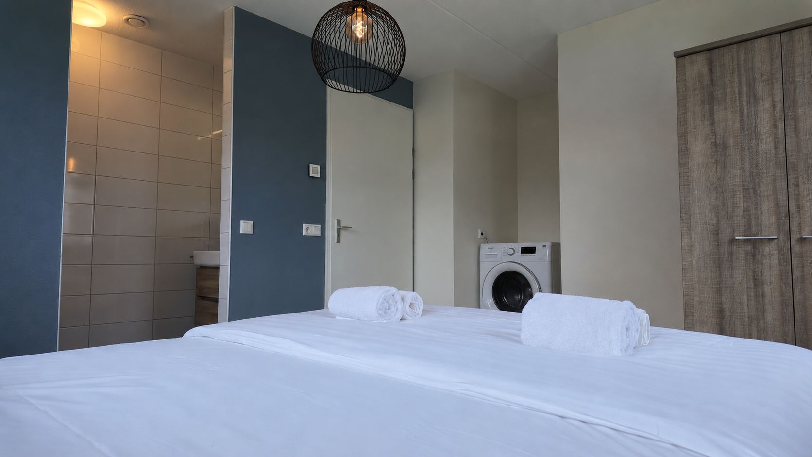 Habitación de hotel con una cama, lavadora y armario.