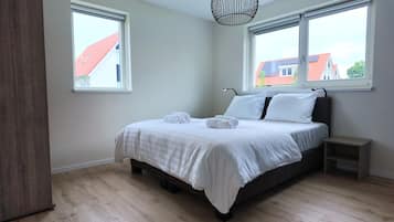Una camera da letto con un letto, due finestre, un comodino e una lampada a sospensione.