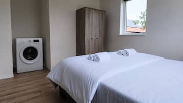 Una camera d'albergo con un letto, un armadio in legno, una lavatrice e una finestra vista edificio.