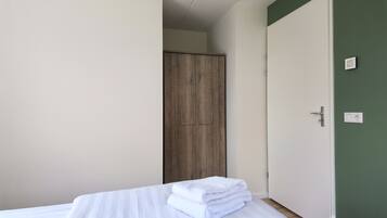 Une chambre d’hôtel avec un lit, une armoire en bois et un mur vert.
