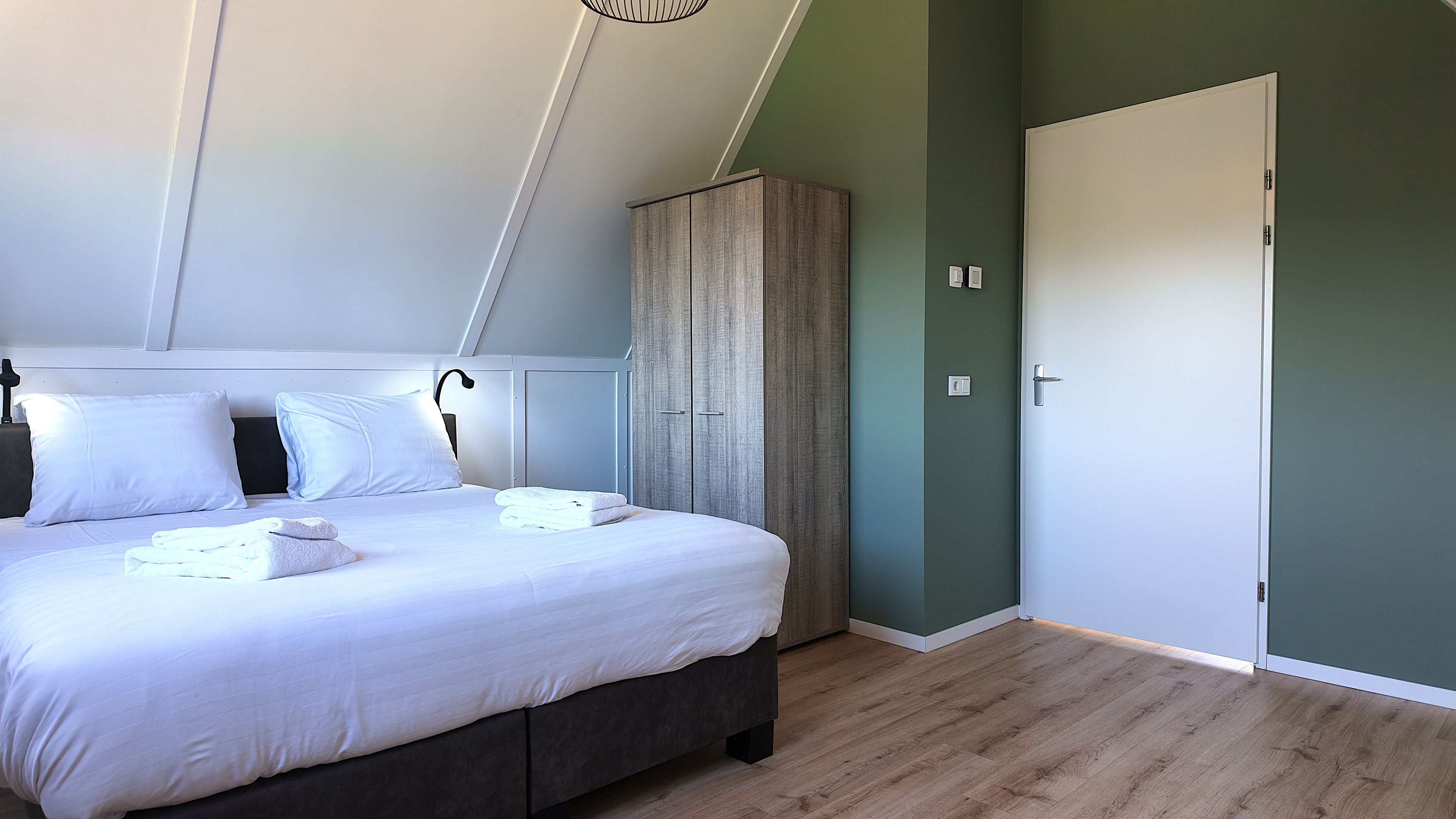 Quarto com cama, guarda-roupa e porta.