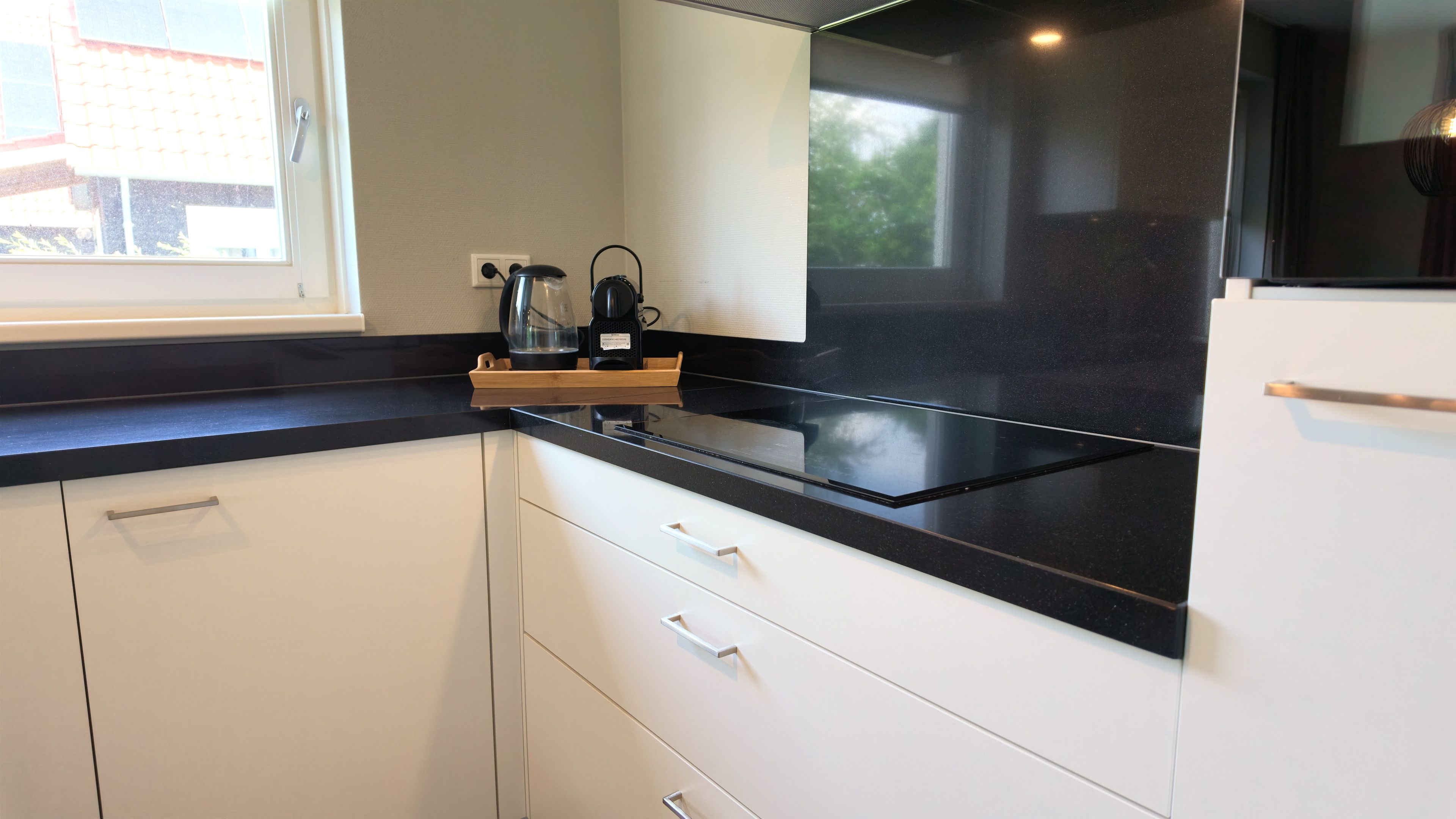 A kitchen with white cabinets, a black countertop, and a built-in oven.