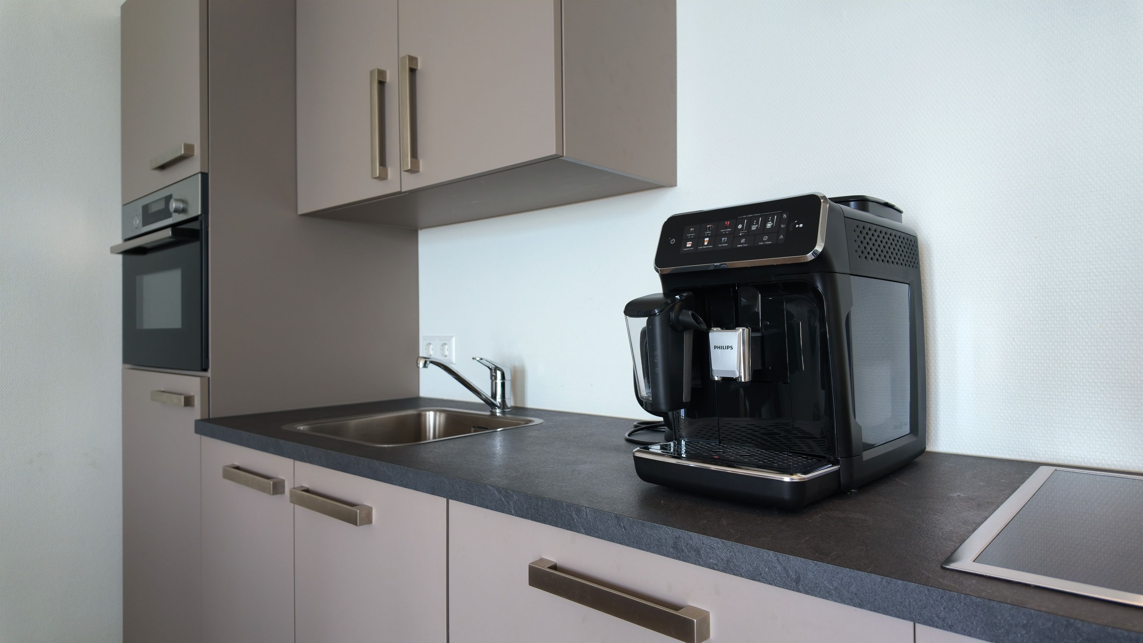 Eine Küche mit Kaffeemaschine, Spüle und Schränken.
