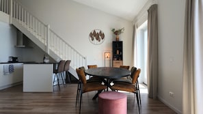 Eine moderne Küche mit Essbereich, Holzboden und einer Treppe.