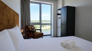 Ein Hotelzimmer mit Bett, Stuhl, Kleiderschrank und einem großen Fenster mit Blick.