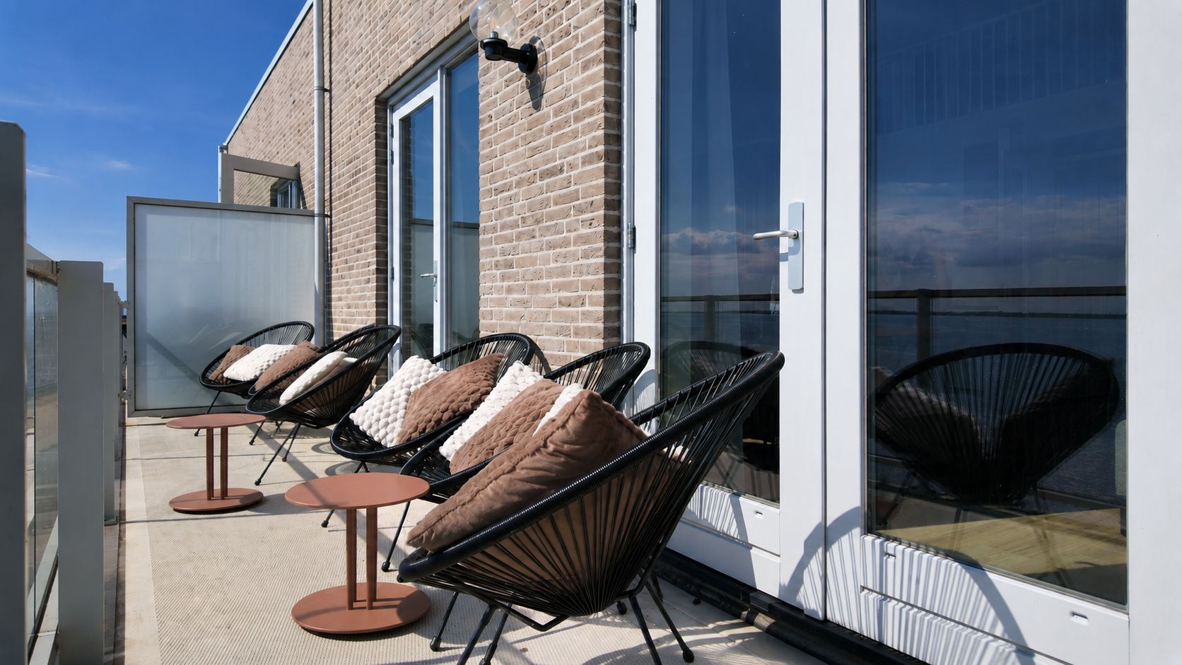 Una terrazza con posti a sedere all'aperto e un ingresso con porta in vetro.