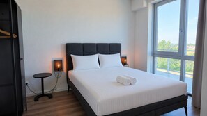 Una habitación de hotel moderna con una cama grande, lámparas de noche, una mesita y un armario.