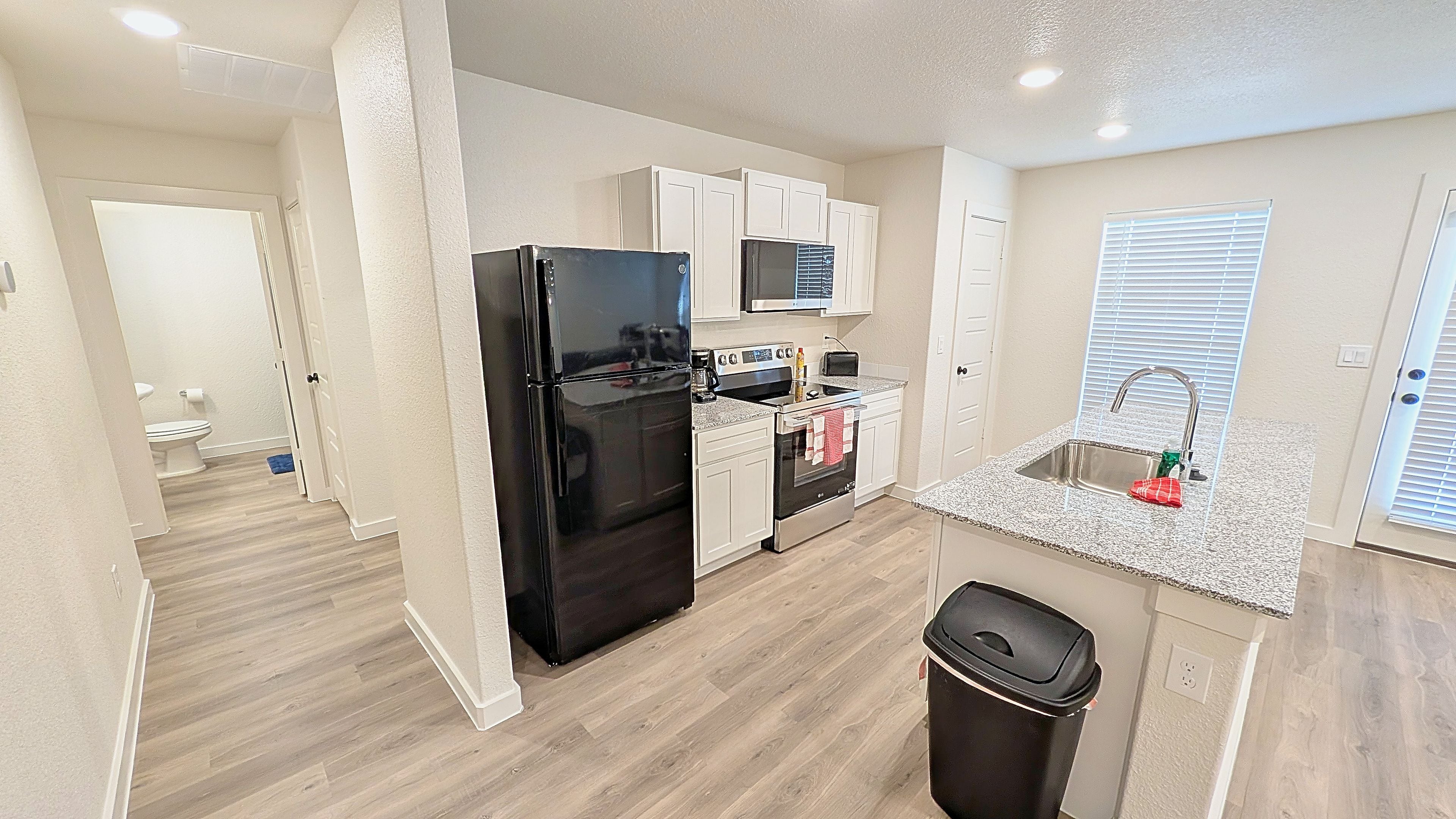 A compact kitchen with a refrigerator, stove, microwave, and sink.
