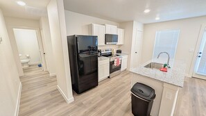 Cocina compacta equipada con refrigerador, estufa, microondas y lavaplatos.