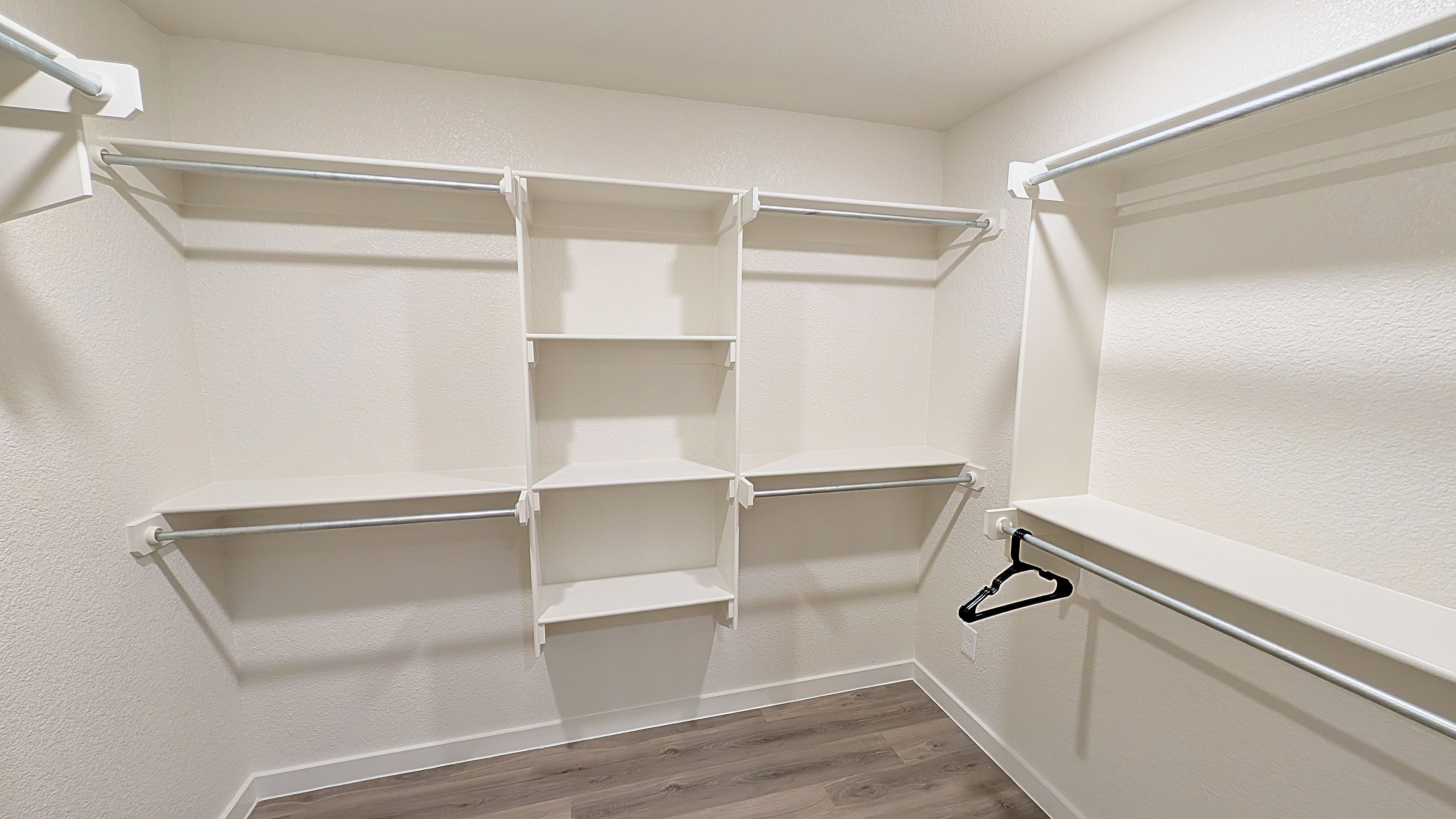 A closet with white shelving units and a wooden floor.