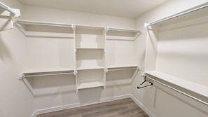 A closet with white shelving units and a wooden floor.